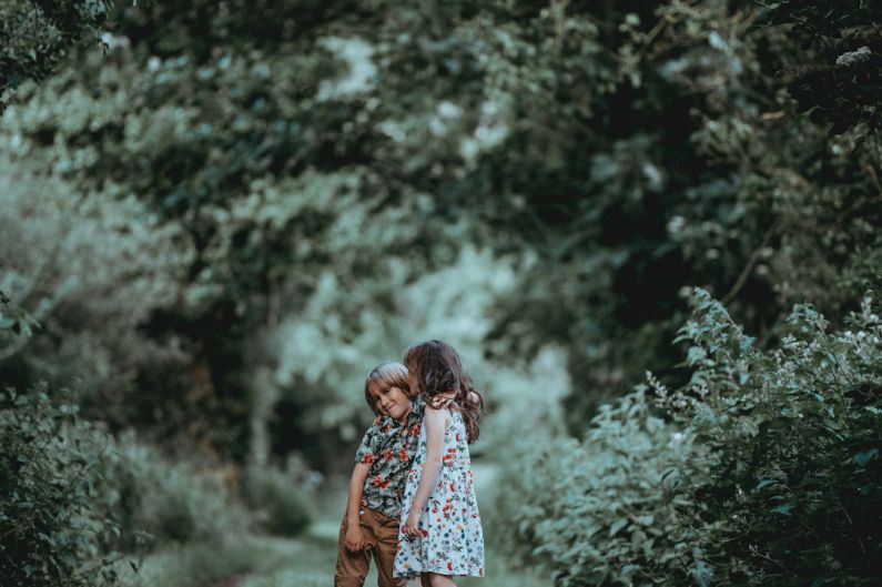 Sibling Rivalry - boy and girl standing in middle of forest trail