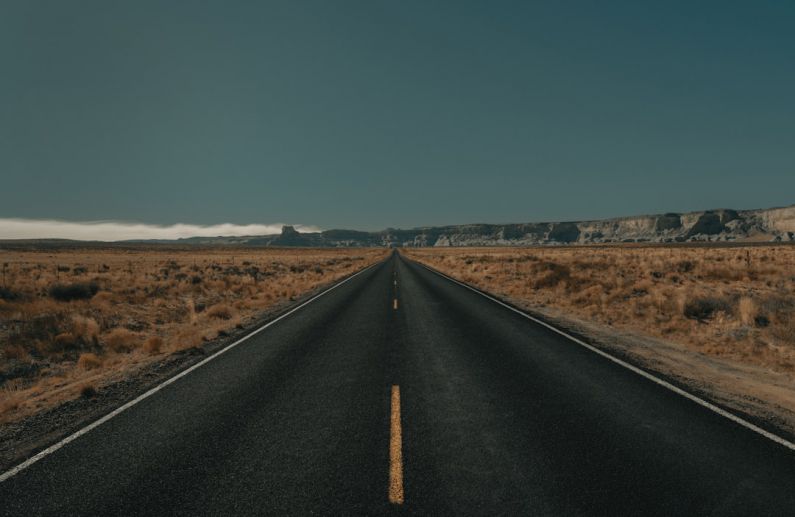 Long-Distance - black asphalt road between brown grass field under blue sky during daytime