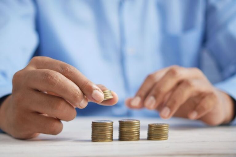 Budget - a person stacking coins on top of a table