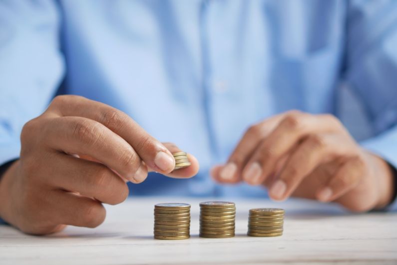 Budget - a person stacking coins on top of a table