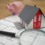 Credit - white and red wooden house beside grey framed magnifying glass