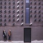 Privacy - two women facing security camera above mounted on structure