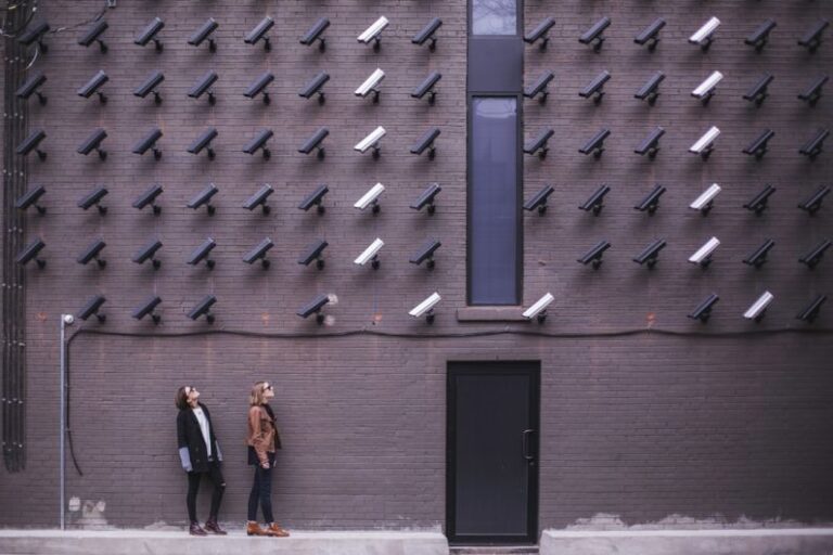 Privacy - two women facing security camera above mounted on structure