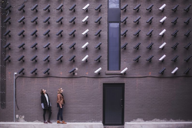 Privacy - two women facing security camera above mounted on structure