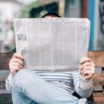 Celebrity News - man sitting on bench reading newspaper