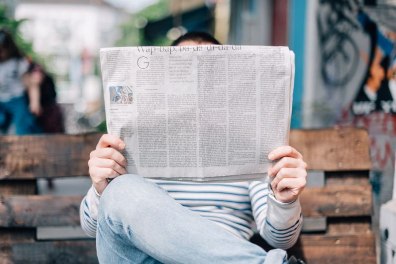 Celebrity News - man sitting on bench reading newspaper