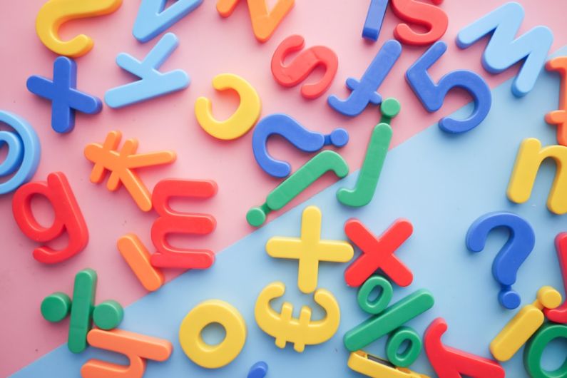 Language - a pile of plastic letters and numbers on a pink and blue background