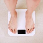 Weight Loss - person standing on white digital bathroom scale