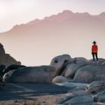 Travel - a person standing on top of a large rock