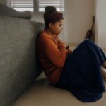 Anxiety - man in orange long sleeve shirt sitting on gray couch