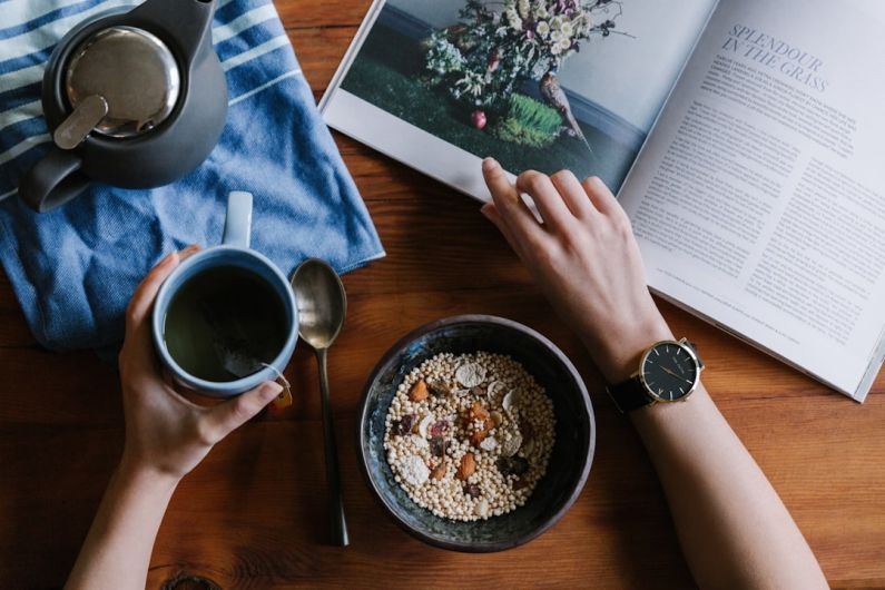 Morning Routine - person holding blue ceramic mug and white magazine