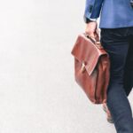 Work - person walking holding brown leather bag