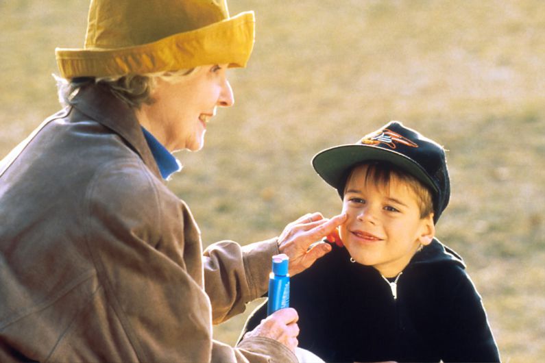 Sun Protection - boy in black hat holding blue plastic bottle