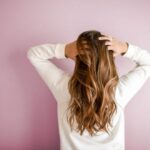 Hair - woman in white long-sleeved shirt standing in front of pink wall